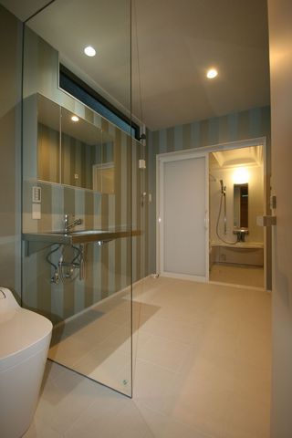 トイレと一体となった洗面室。ガラスやステンレスを採用することで、ホテルのような非日常的な空間に。